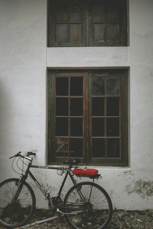 a bicycle leaning against the side of an old building with a window