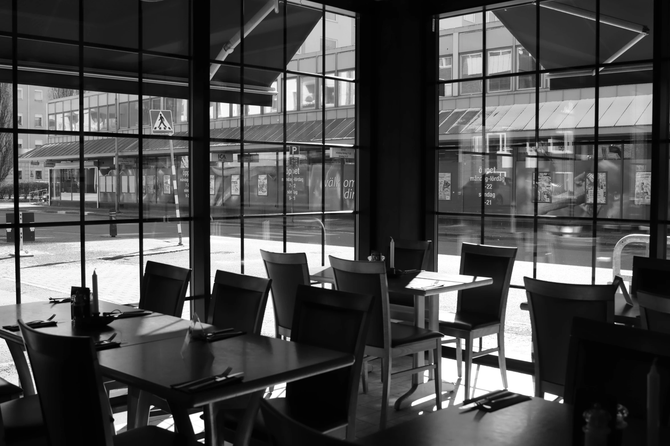 a dining room with windows in the middle and several tables on either side