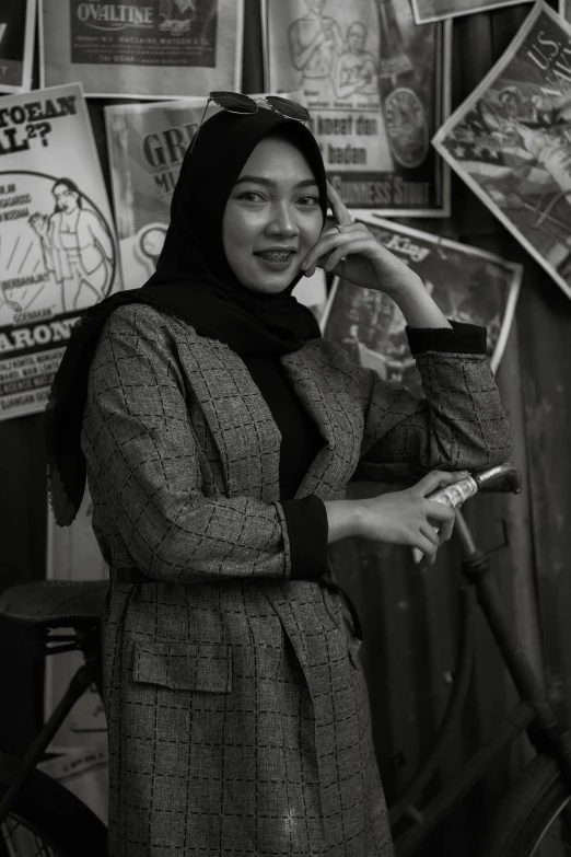 a woman is standing in front of a wall covered with posters