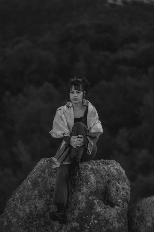 woman wearing jacket sitting on rock in dark area