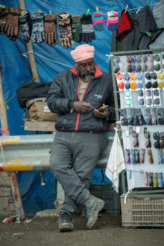 a man standing in front of a market area checks his phone