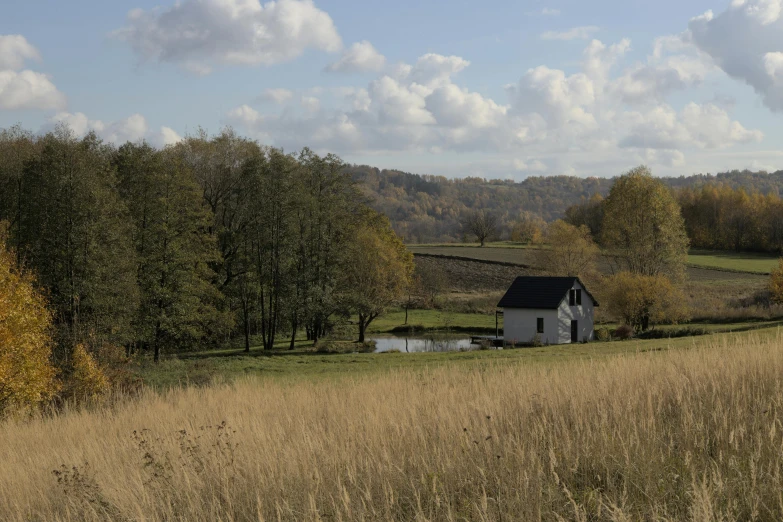 a barn in the middle of a field near a body of water