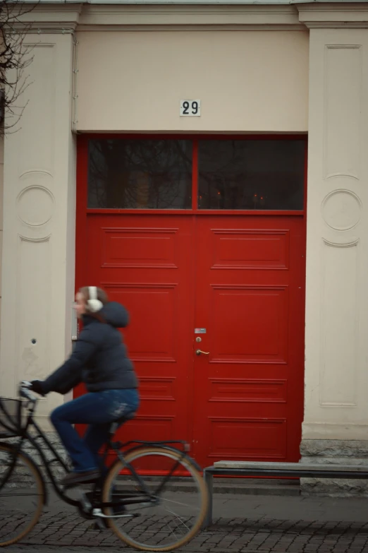 a man on a bike rides past a red door