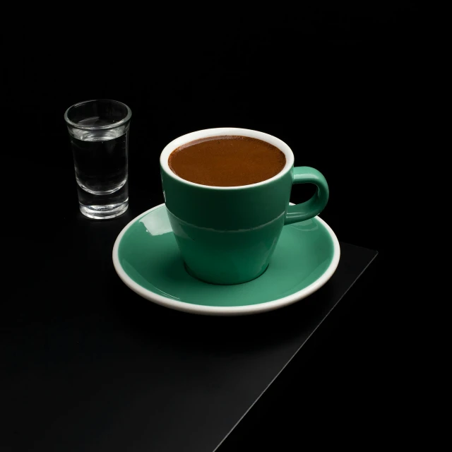 there is a cup of coffee and a glass on the table