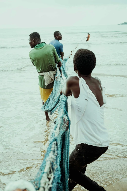 four people preparing their fishing nets on the beach