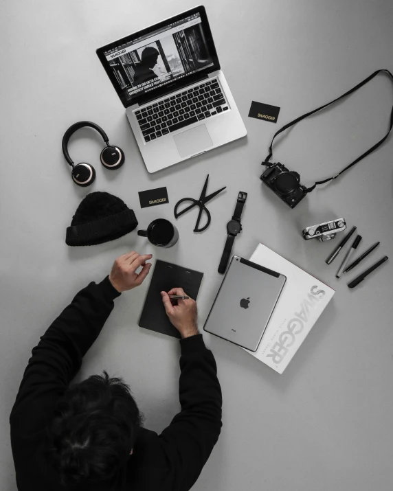 a person writing on a laptop while holding a pen