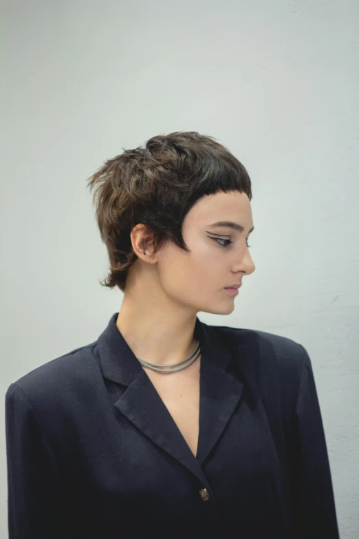 a woman with black hair is wearing a suit and necklace