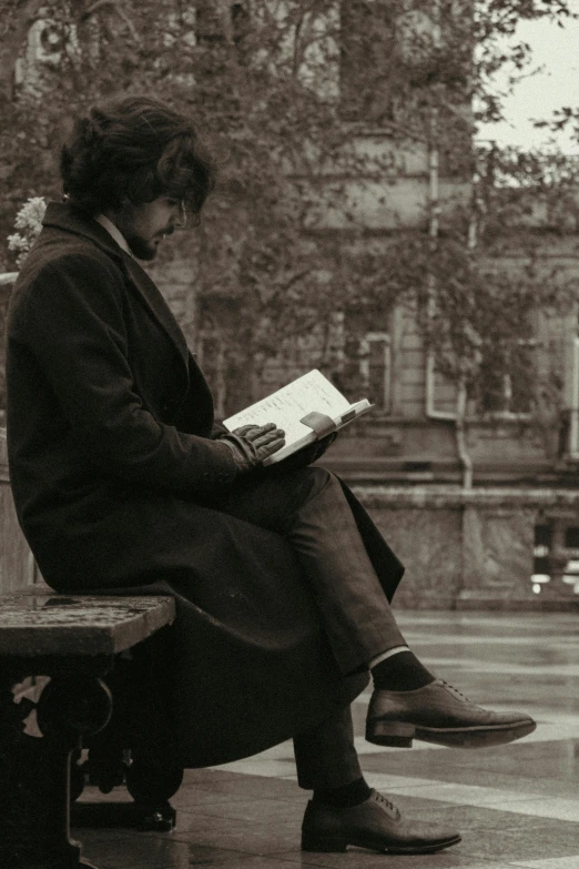 a man sitting on top of a bench reading