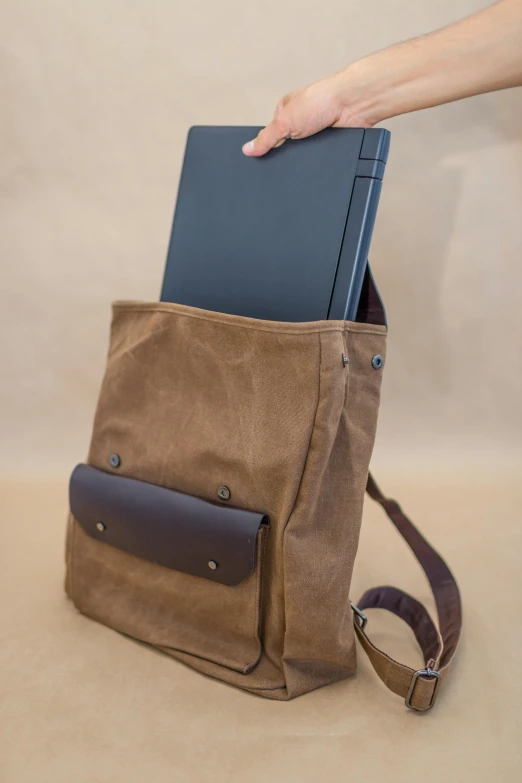 someone is holding a brown bag over the back pocket of their computer