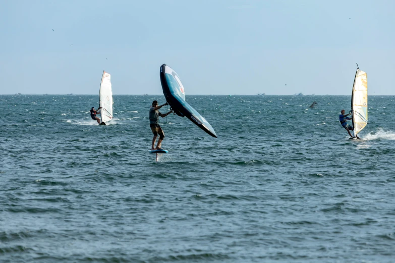 three windsurfers are out in the water in the day