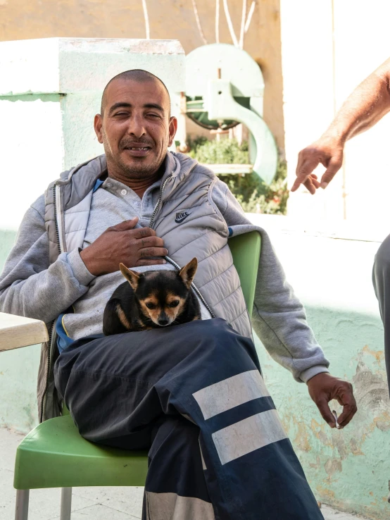 an older man sitting in a chair with a small dog