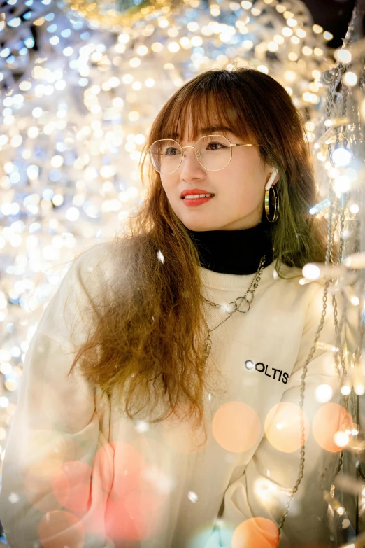 a woman wearing a white shirt and earrings in front of a wall of lights