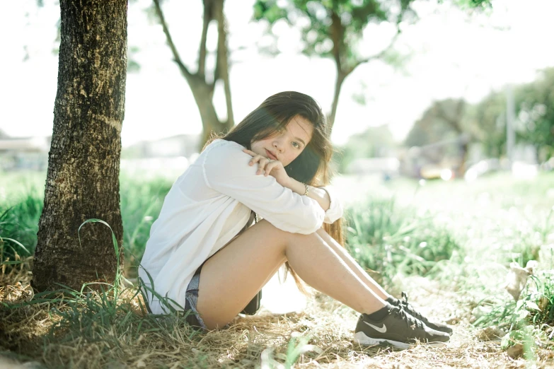 a woman sitting under a tree wearing shoes