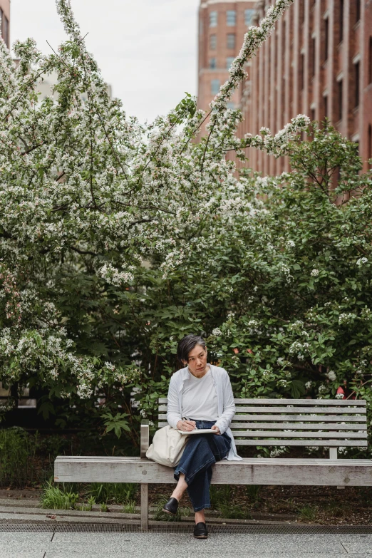 a woman sits on a bench and looks at her book