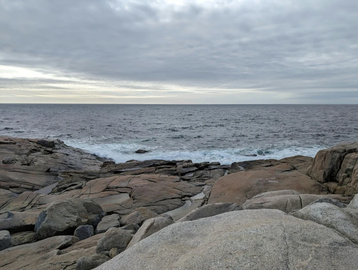 a person is standing on some rocks by the water