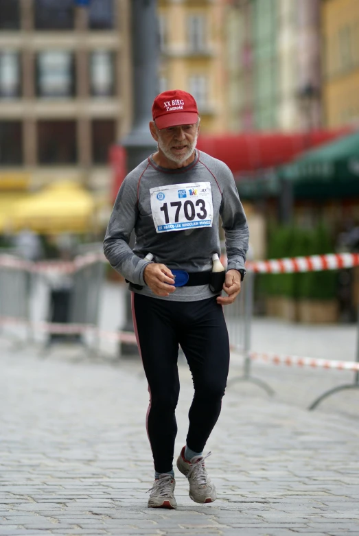 a man with a hat and red sweat cap running in a marathon