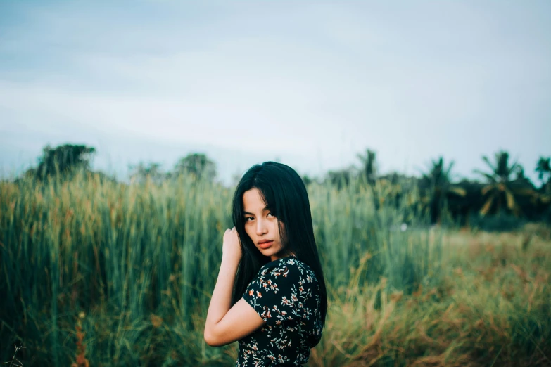 a woman standing in a field in a dark dress