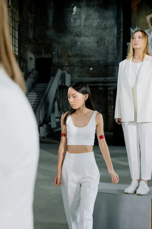 two women walking on the runway wearing white outfits