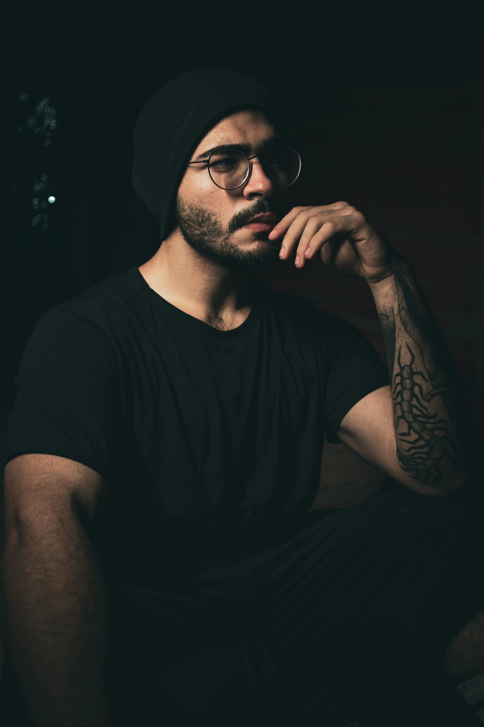 a man with black hat and glasses sitting down