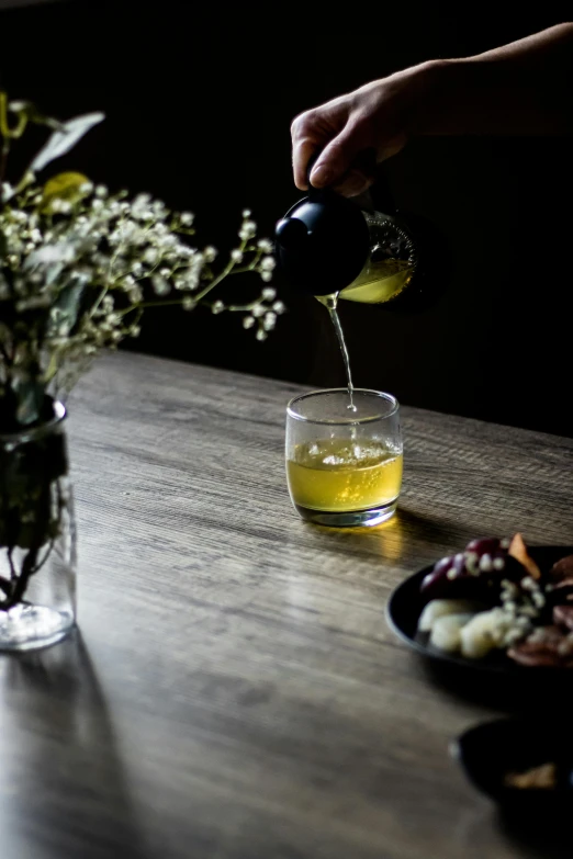 someone pours juice from a black bottle into a glass