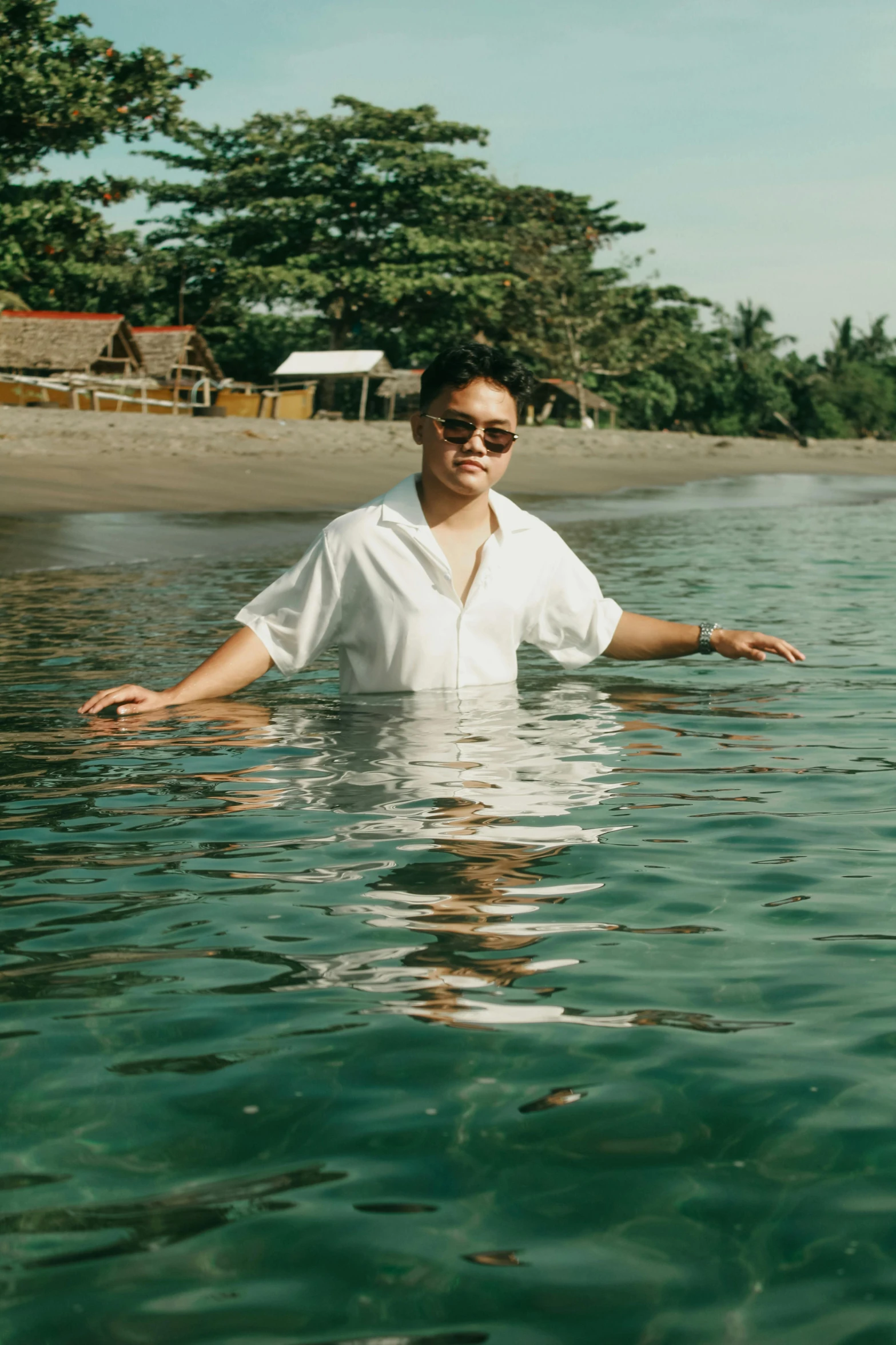 a man floating in water with his arms spread out and a house in the background