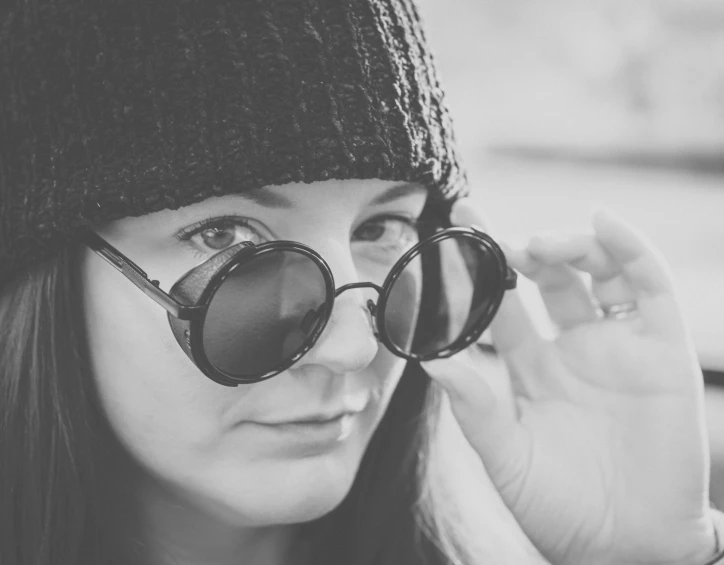 a girl wearing sunglasses and a knitted hat on her head is talking on the phone