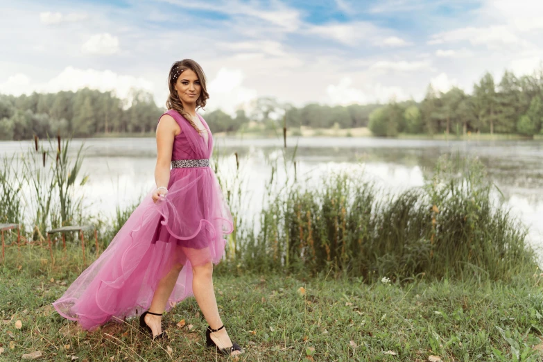 the woman is standing by the water wearing a pink dress