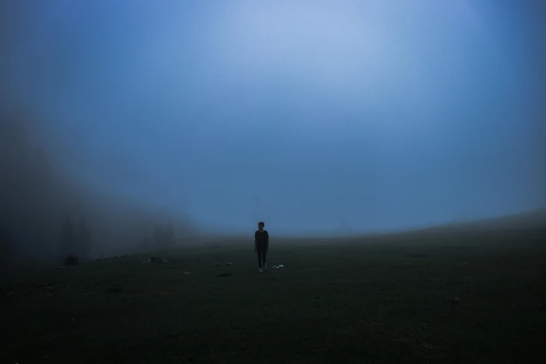 a man standing in the fog on a grassy field