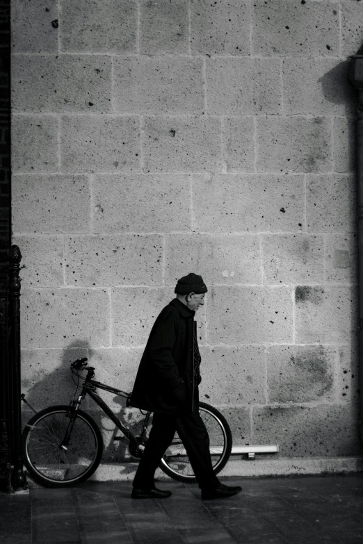 a man with a bike walks down a brick sidewalk