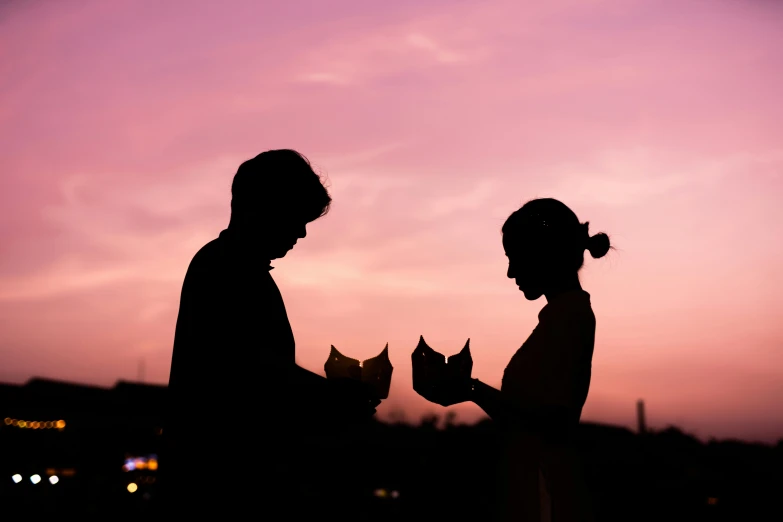 two people stand near each other as the sun sets