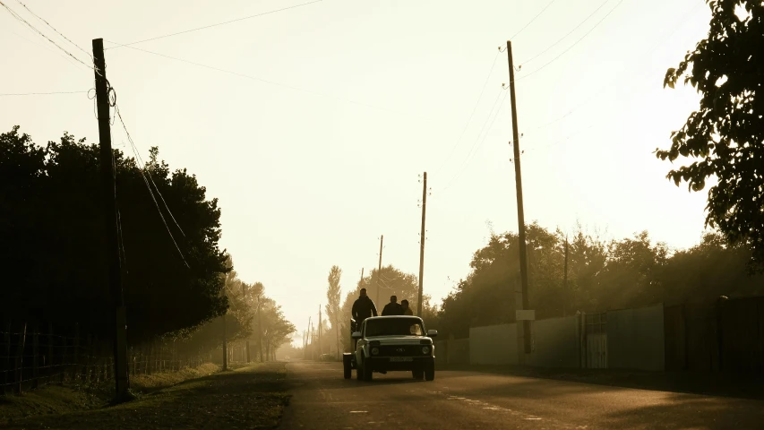 a small pickup truck with two people in the back driving down a road