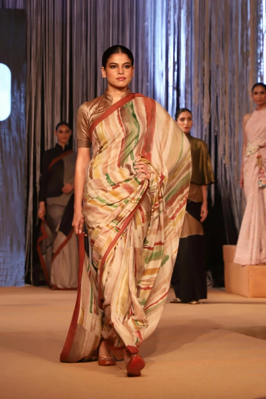 a female model is walking down the catwalk in a sari