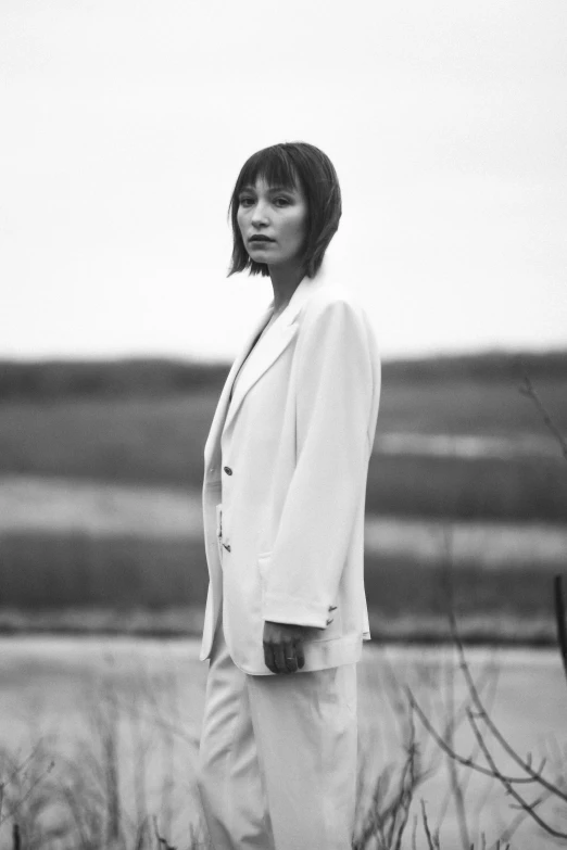 a woman standing in a field, wearing white