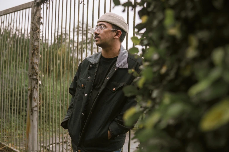 a man in a hat standing outside of a gate