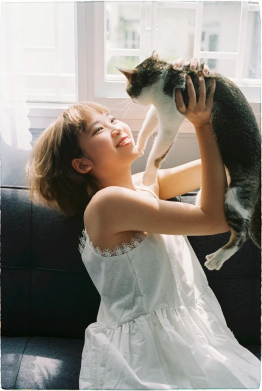 a woman in a white dress is holding a cat