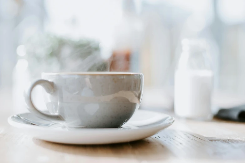 a white coffee cup on a saucer on a wood table