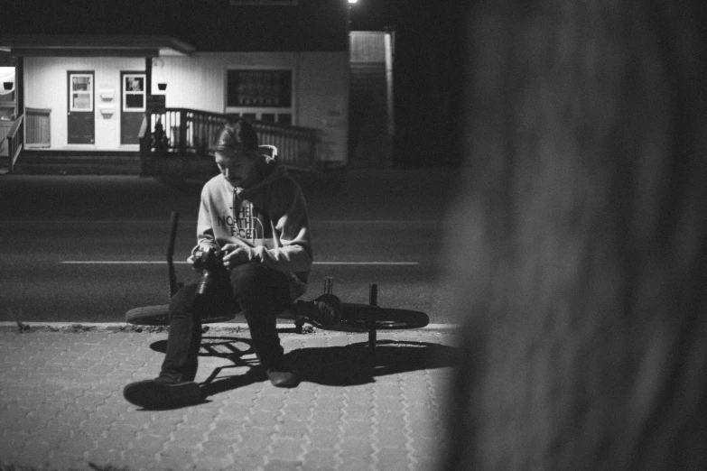 two people sit at an outdoor bench under some lights