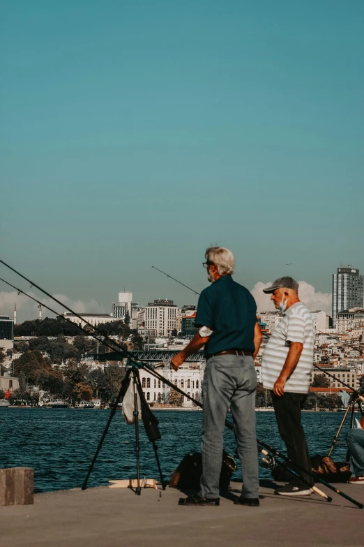 two men are fishing at the beach while two women watch