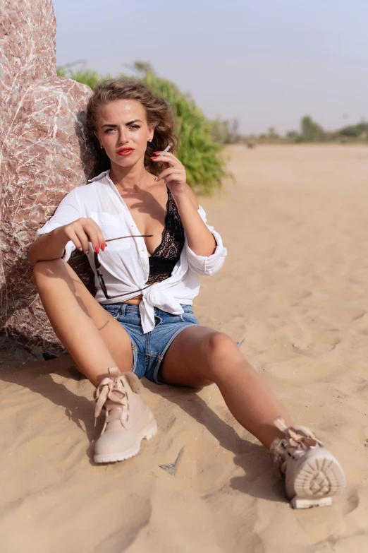 the woman is posing in denim shorts and an open white jacket