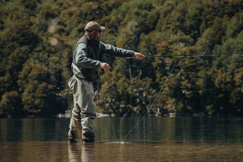 a man fishing on the water with trees in the background