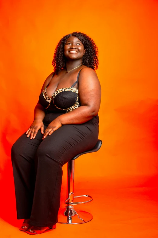 a woman sitting on top of a chair next to an orange wall