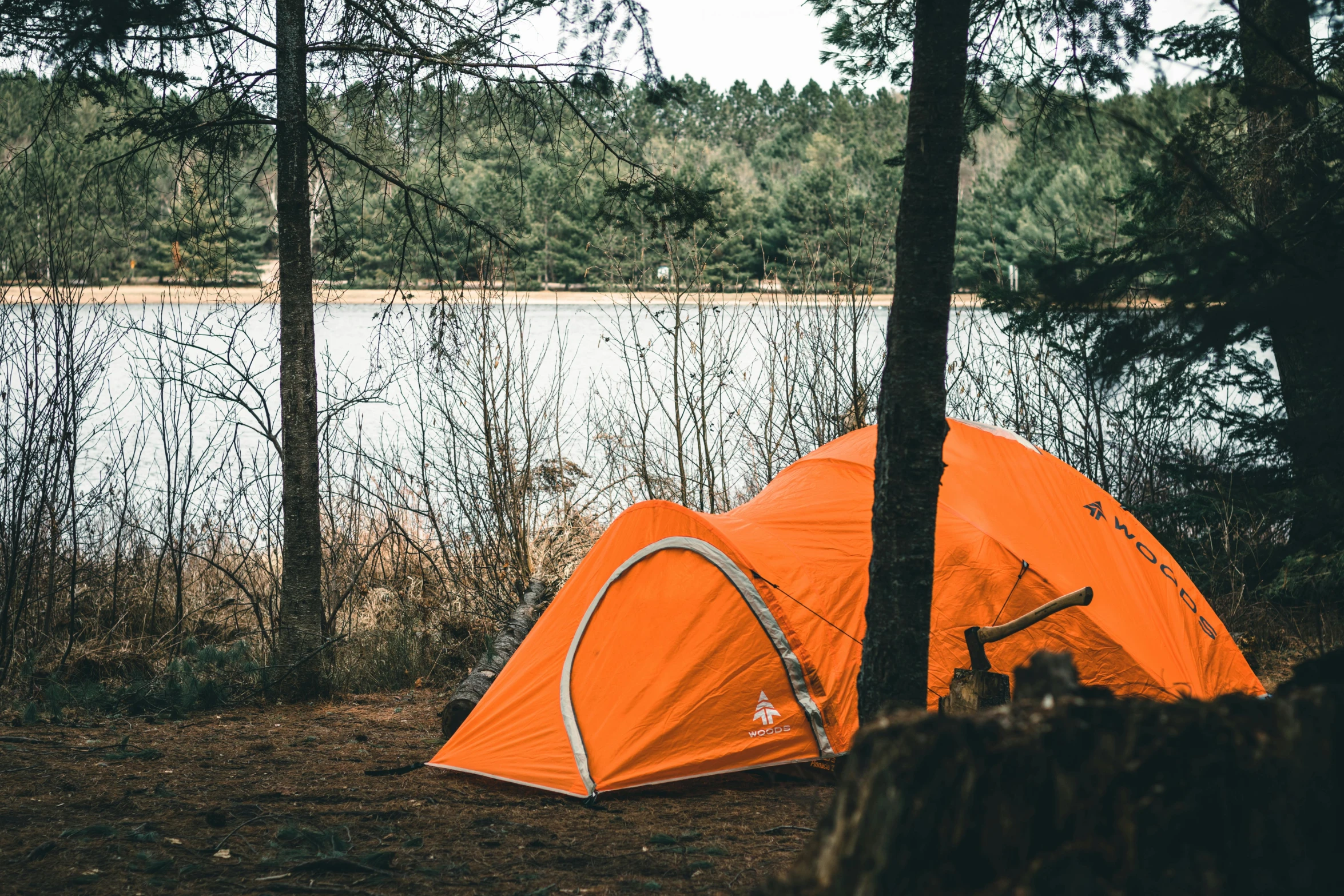 the tent is set up next to the trees on the shore of the lake