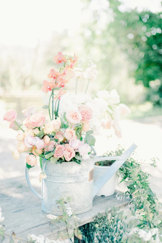 watering can full of flowers on a table