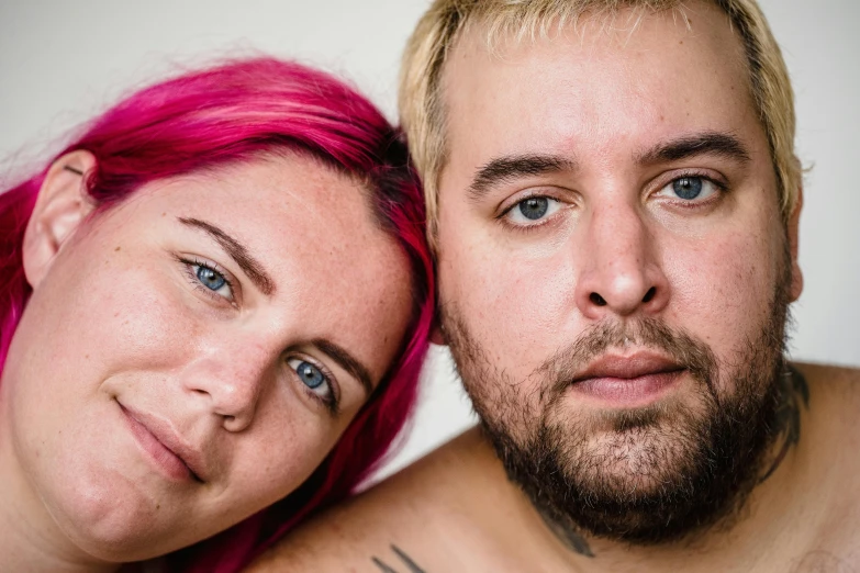 a woman standing next to a man with pink hair