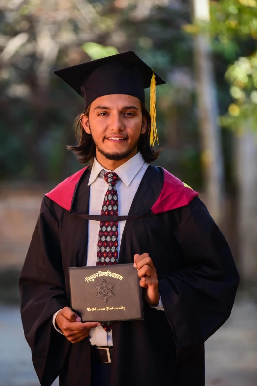 man in graduation gown with diploma posing for the camera