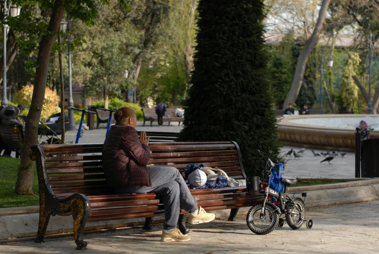 a person is sitting on the bench talking on her cell phone