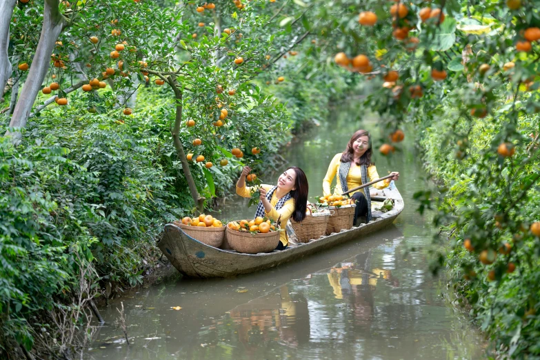 two women sitting in a boat filled with oranges