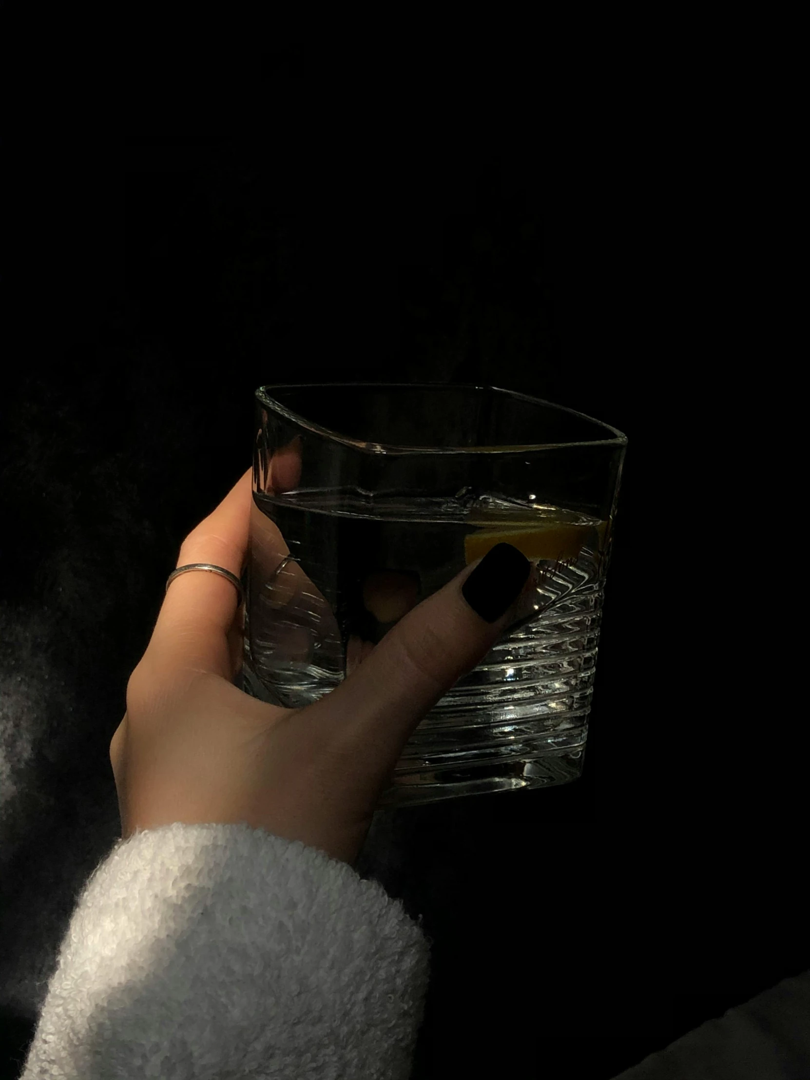 a person's hand holding a glass that is partially filled with soing