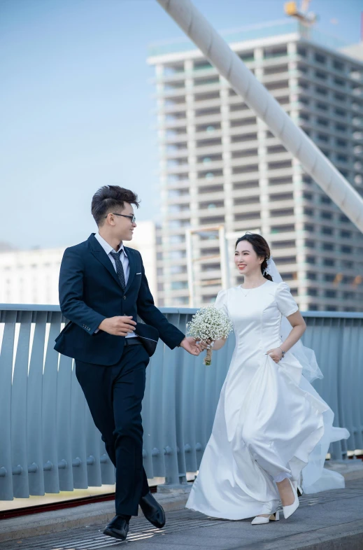 a young bride and groom smile as they walk along a street in the city