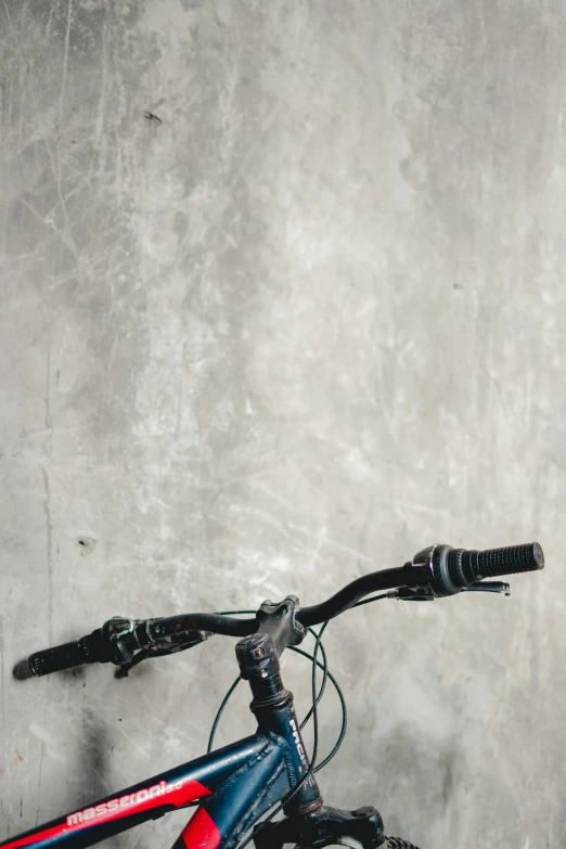 a bicycle parked against a concrete wall with a handlebar